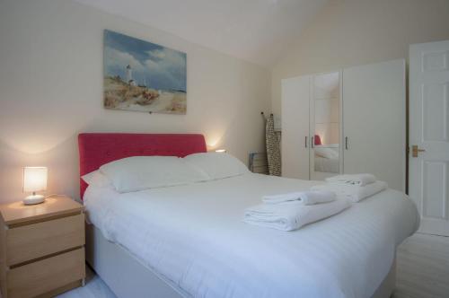 a bedroom with a white bed with a red headboard at Campbell - 2 Bedroom Apartment - Pendine in Pendine