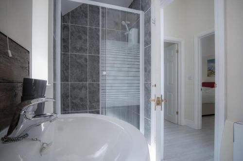 a bathroom with a white sink and a shower at Campbell - 2 Bedroom Apartment - Pendine in Pendine
