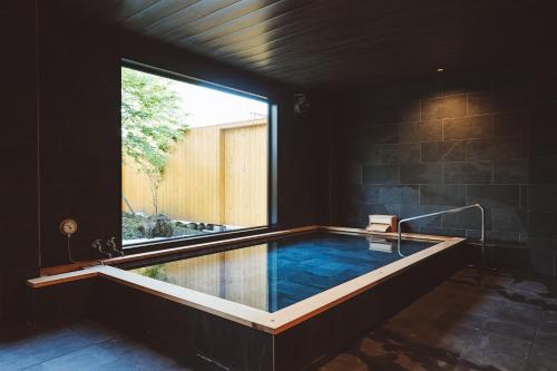 Cette chambre dispose d'une grande baignoire et d'une grande fenêtre. dans l'établissement 蓼科BASE kitchen,spa&hotel, à Chino