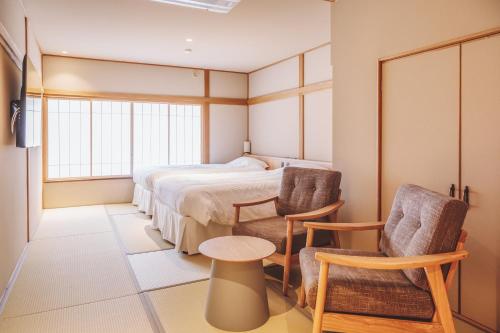 1 Schlafzimmer mit einem Bett, 2 Stühlen und einem Tisch in der Unterkunft 蓼科BASE kitchen,spa&hotel in Chino