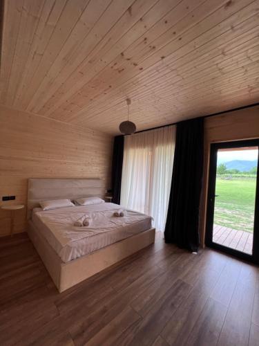 een slaapkamer met een groot bed en een groot raam bij Chubini Winery & Cabins in Kvareli