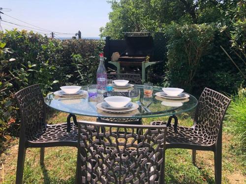 une table en verre avec des chaises et une bouteille d'eau dans l'établissement Le jardin suspendu, à Rillieux-la-Pape