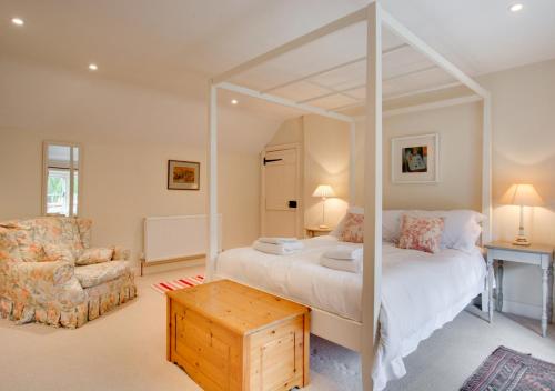 a bedroom with a large white bed and a chair at Byre Cottage in Langham