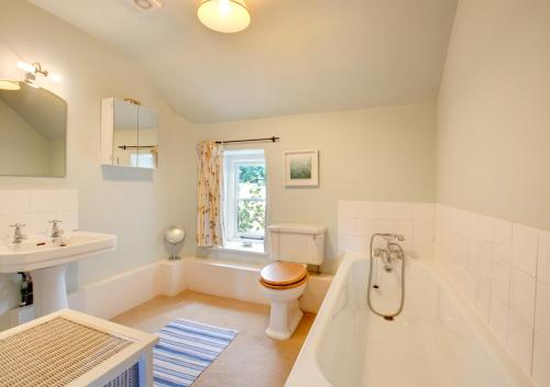 a bathroom with a tub and a toilet and a sink at Byre Cottage in Langham