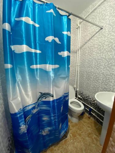 La salle de bains est pourvue d'un rideau de douche avec des poissons. dans l'établissement Мини-студия напротив парка Металлургов, à Öskemen
