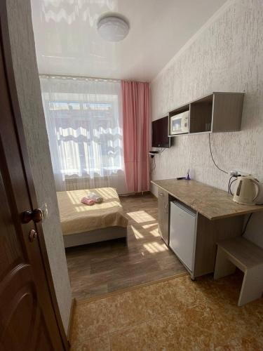 a small room with a bed and a kitchen at Мини-студия напротив парка Металлургов in Ustʼ-Kamenogorsk