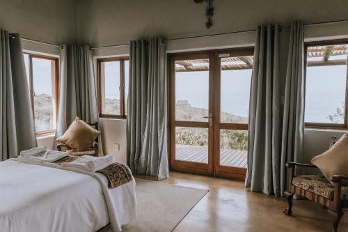 a bedroom with a bed and a large window at Ocean View Cottage, Springerbaai in Boggomsbaai