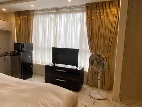 een slaapkamer met een bed, een televisie en een ventilator bij Luxe Suites Bahria Town Lahore in Lahore