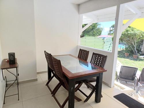 a dining room with a glass table and chairs at La Rose du Bresil Marie-Galante in Capesterre-de-Marie-Galante