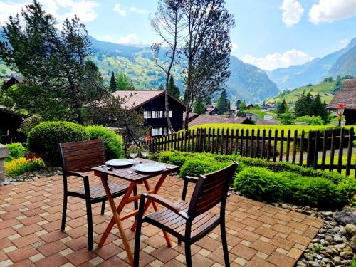 una mesa y 2 sillas en un patio de ladrillo con montañas en MOM - Alpine Boutique Apartments, Chalet Fagus, Terrace Studio, en Grindelwald