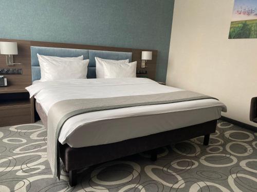 a bedroom with a large bed with white sheets and pillows at Holiday Inn Dąbrowa Górnicza-Katowice by IHG in Dąbrowa Górnicza