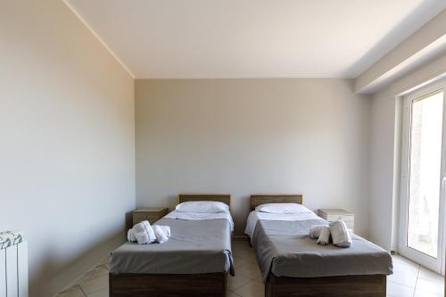 two twin beds in a room with a window at Elements Holiday in Castelforte