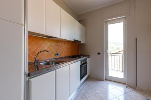 eine Küche mit weißen Schränken, einem Waschbecken und einem Fenster in der Unterkunft Elements Holiday in Castelforte