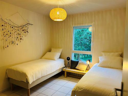 1 dormitorio con 2 camas y ventana en Gîte Ethic Simple & Chic, en Labastide-Marnhac
