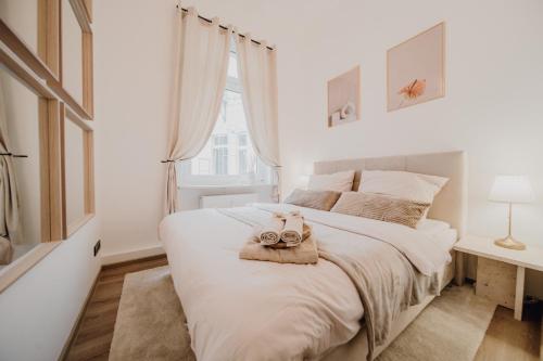 um quarto com uma cama branca com duas toalhas em LLR Design Apartment - Sienna Beige im Zentrum von Koblenz em Koblenz