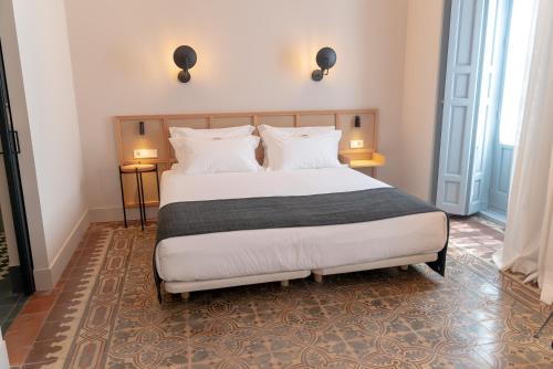 a bedroom with a large bed with white sheets and pillows at Casa del Médico Hotel Boutique in Alcázar de San Juan