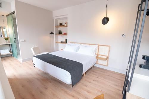 a bedroom with a white bed and a wooden floor at Casa del Médico Hotel Boutique in Alcázar de San Juan