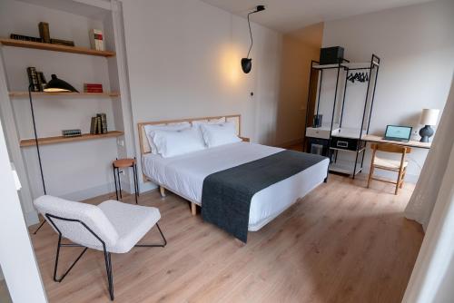 a bedroom with a large white bed and a chair at Casa del Médico Hotel Boutique in Alcázar de San Juan