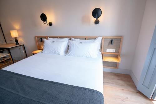 a bedroom with a bed with white sheets and pillows at Casa del Médico Hotel Boutique in Alcázar de San Juan