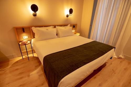 a bedroom with a large bed with white sheets and pillows at Casa del Médico Hotel Boutique in Alcázar de San Juan