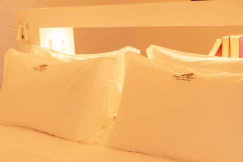 a bed with white pillows on top of it at Casa del Médico Hotel Boutique in Alcázar de San Juan