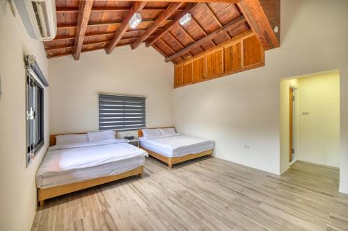 two beds in a room with wooden ceilings and wooden floors at 澎湖奇遇菓海景民宿 in Xiyu