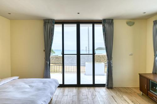 een slaapkamer met een bed en uitzicht op de oceaan bij 澎湖奇遇菓海景民宿 in Xiyu