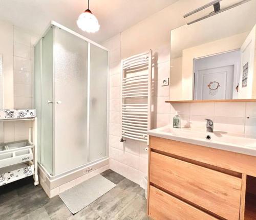 une salle de bain blanche avec une douche et un lavabo dans l'établissement Maison avec terrasse cosy, 2 chambres, wifi, parking, à Ruelle-sur-Touvre