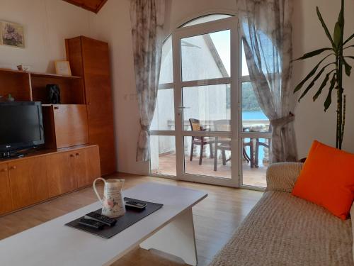 a living room with a couch and a tv and a table at Apartments Sponga in Polače