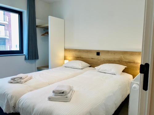 1 dormitorio con 2 camas y toallas. en Belcasa Mar Suites & Lofts, en Middelkerke