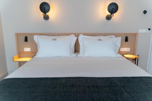 a bedroom with a white bed with two pillows at Casa del Médico Hotel Boutique in Alcázar de San Juan