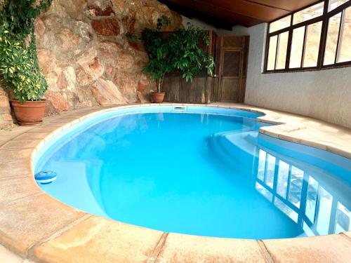 a large blue swimming pool with a stone wall at Casa Cueva LA PARRA. in Terque