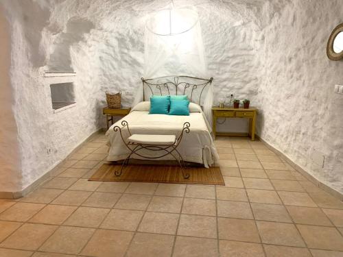 a bedroom with a bed with blue pillows on it at Casa Cueva LA PARRA. in Terque