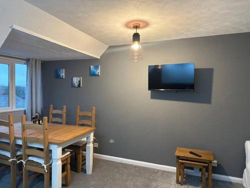 a dining room with a table and a television on a wall at Faldouet 3 bed flat in Rock in Saint Minver