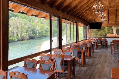 una fila di tavoli e sedie in una stanza con un fiume di Modra Rijeka Resort a Glavatičevo