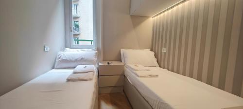 2 camas en una habitación pequeña con ventana en Brera - Marcora 6 b luxury living, en Milán