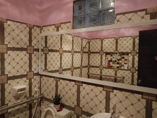 a bathroom with a tiled wall with a toilet at Leigh HomeStay in Alaminos