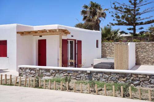 a white house with red doors and a stone wall at Casa Philippi Suites in Mýkonos City