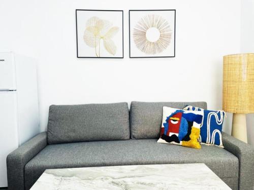 szara kanapa w salonie z dwoma zdjęciami na ścianie w obiekcie Apartamento ALAZUL Soberao w mieście Conil de la Frontera