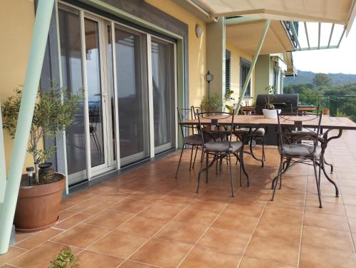 eine Terrasse mit einem Tisch und Stühlen auf dem Balkon in der Unterkunft Villa Capogrecale in Piedimonte Etneo