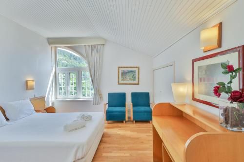 a hotel room with a bed and two blue chairs at Morgado - River Suites and Houses by PCH in Padrões