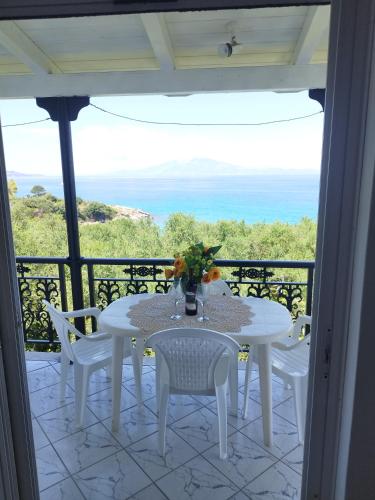 una mesa y sillas en un balcón con vistas al océano en VILLA AGIA AIKATERINI en Amoudi