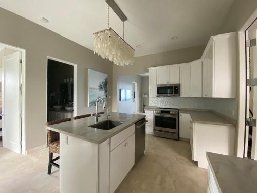 a kitchen with white cabinets and a sink at Sunset Reef St. Kitts in Ottleyʼs