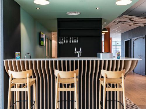 a kitchen with a bar with three stools at B&B HOTEL Sélestat Centre-Alsace in Sélestat