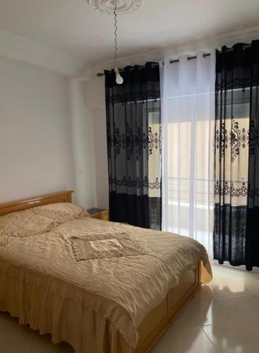 1 dormitorio con 1 cama y una ventana con cortinas en Résidence bades en Alhucemas
