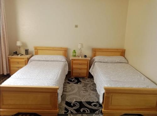 1 dormitorio con 2 camas y 2 mesitas de noche en Résidence bades en Alhucemas