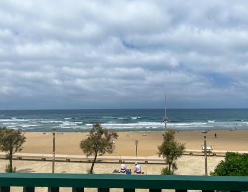 a view of a beach with a green bench at Hotel Arimune in Bakio