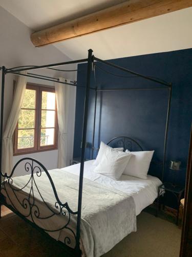1 dormitorio con cama negra con dosel y almohadas blancas en Le Jardin sur la colline, en LʼIsle-sur-la-Sorgue