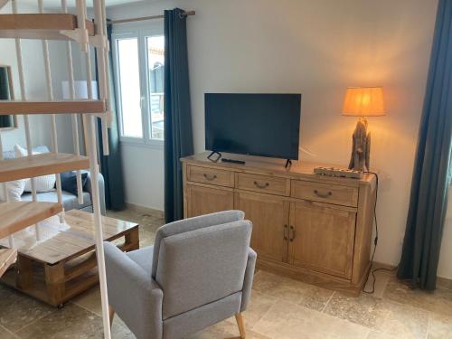 ein Wohnzimmer mit einem TV und einem Stuhl in der Unterkunft Appartement neuf coeur du village in Saintes-Maries-de-la-Mer