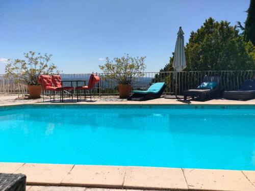 a blue swimming pool with chairs and an umbrella at Bastide vue exceptionnelle in Aix-en-Provence